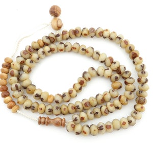 Könnte beinhalten: Ein beige-braunes Gebetsrosenkranz mit Holzperlen und einem Quasten. Die Perlen sind aus natürlichen Materialien gefertigt und haben ein einzigartiges Muster.
