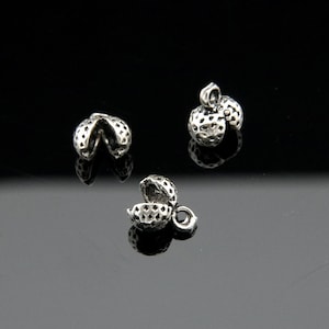 May include: Three silver metal cord end caps. Two are closed and one is open. The caps have a textured surface.