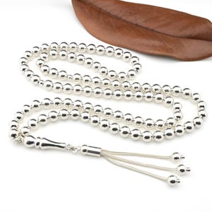 May include: A silver prayer beads necklace with a tassel. The beads are round and smooth.