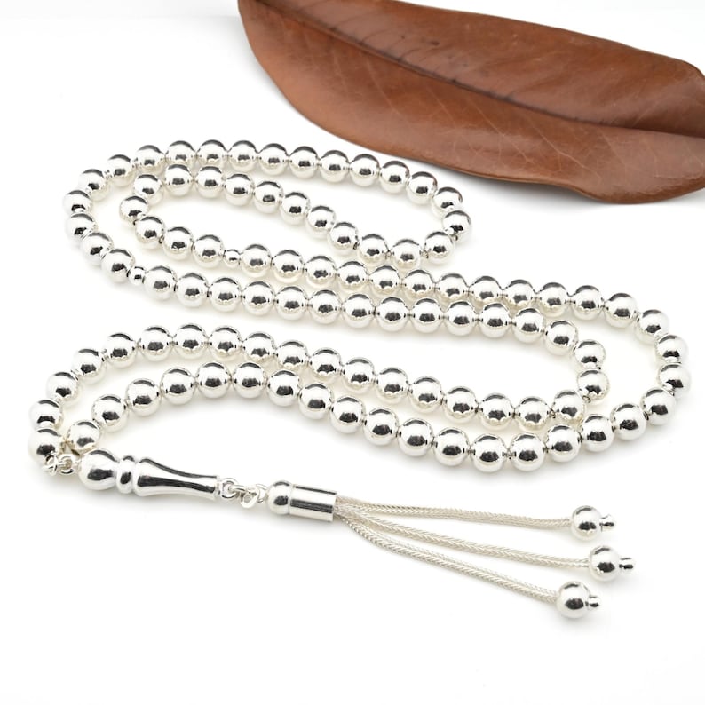 May include: A silver prayer beads necklace with a tassel. The beads are round and smooth.