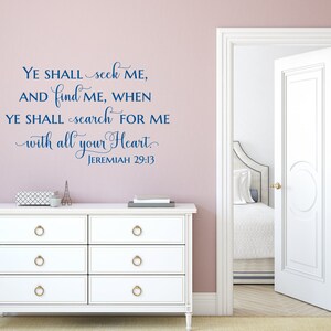 Puede incluir: Una c&oacute;moda blanca con pomos dorados contra una pared rosa claro con una calcoman&iacute;a de pared de vinilo azul que dice "YE SHALL seek ME, AND find ME, WHEN YE SHALL search FOR ME with all your Heart. JEREMIAH 29:13".