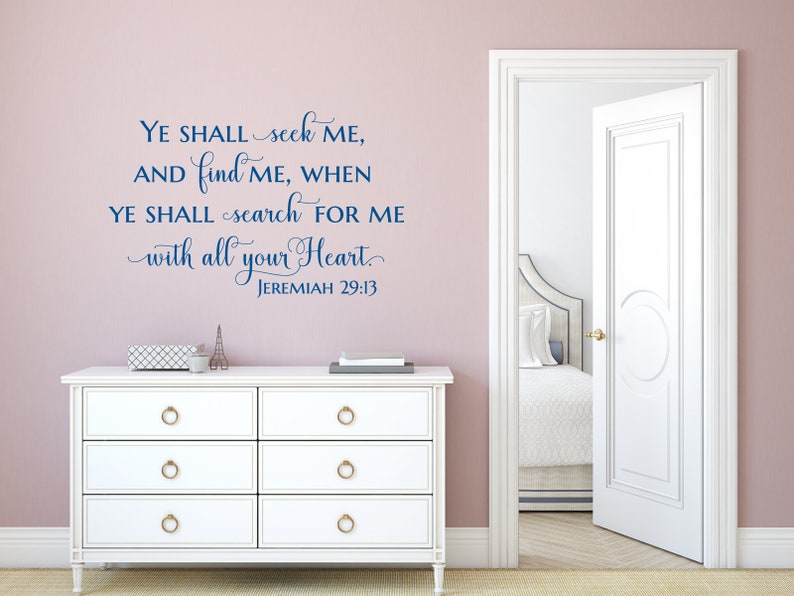 Puede incluir: Una c&oacute;moda blanca con pomos dorados contra una pared rosa claro con una calcoman&iacute;a de pared de vinilo azul que dice "YE SHALL seek ME, AND find ME, WHEN YE SHALL search FOR ME with all your Heart. JEREMIAH 29:13".
