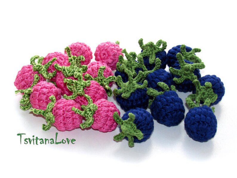 K&ouml;nnte beinhalten: Eine Sammlung geh&auml;kelter Himbeeren und Blaubeeren. Die Himbeeren sind rosa und die Blaubeeren sind blau. Beide sind mit gr&uuml;nen Bl&auml;ttern verziert.
