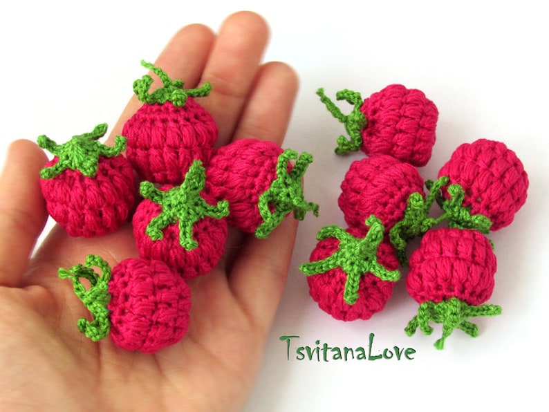K&ouml;nnte beinhalten: Eine Sammlung von neun geh&auml;kelten Erdbeeren in Rosa- und Gr&uuml;nt&ouml;nen. Die Erdbeeren sind klein und haben ein realistisches Aussehen.