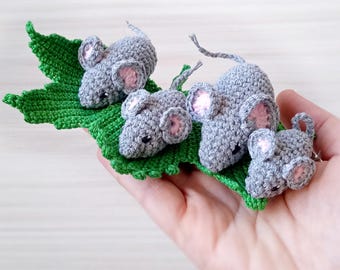 Può includere: Quattro topi di uncinetto grigi con orecchie rosa sono seduti su una foglia di uncinetto verde.