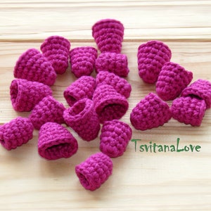 May include: A collection of 17 crocheted pink flower-shaped embellishments. The embellishments are made of yarn and have a textured surface.