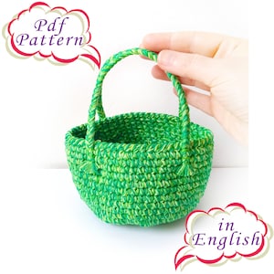 May include: Green and white crocheted basket with a handle. The basket is small and has a round shape. The text "Pdf Pattern in English" is visible in the image.