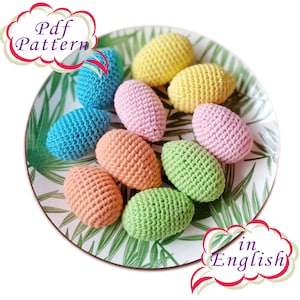 May include: A plate of crocheted Easter eggs in various colors, including pink, blue, green, yellow, and orange. The plate has a green leaf design. The text "Pdf Pattern in English" is visible in the image.
