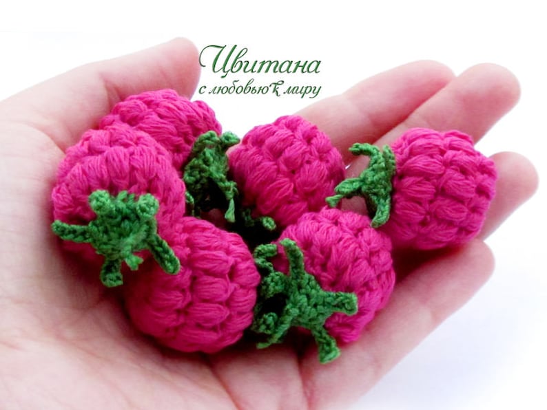 K&ouml;nnte beinhalten: Nahaufnahme von sechs geh&auml;kelten pinkfarbenen Himbeeren mit gr&uuml;nen Bl&auml;ttern. Die Himbeeren sind in einer Hand angeordnet, wobei die Bl&auml;tter nach au&szlig;en zeigen.