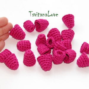 May include: A collection of 18 crocheted raspberry-shaped embellishments in a vibrant pink color. The embellishments are made with a fine yarn and have a delicate texture.