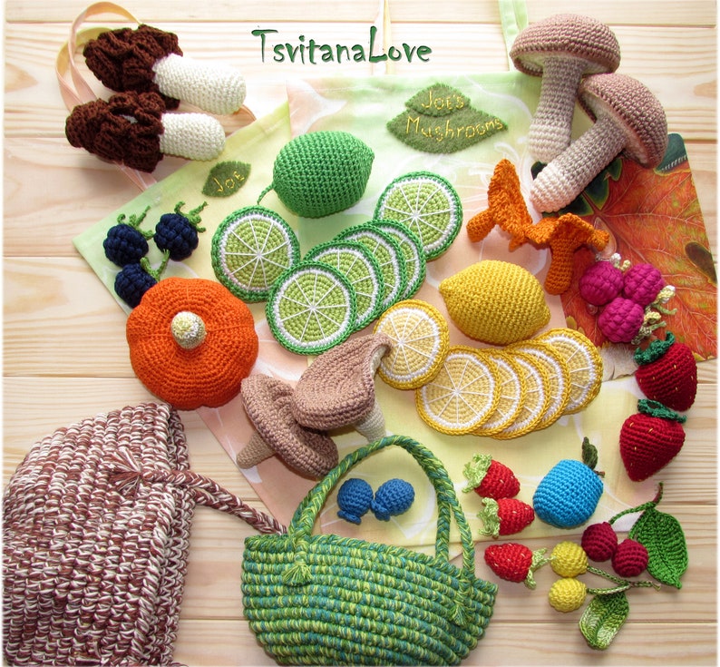 May include: A collection of crocheted food items, including mushrooms, limes, lemons, strawberries, blueberries, and a poppy. The items are arranged on a wooden surface with a green and brown tote bag in the background. The tote bag has the text "Jo's Mushrooms" and "TsvitanaLove" printed on it.