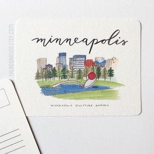 May include: Watercolor postcard featuring the Minneapolis skyline and the Spoonbridge and Cherry sculpture. The word "minneapolis" is written in cursive. The bottom of the card reads "Minneapolis Sculpture Garden".