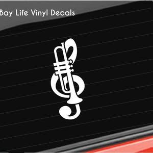 May include: White vinyl decal featuring a musical treble clef combined with a trumpet. The decal is on a black background. The text "Bay Life Vinyl Decals" is in the upper left corner.