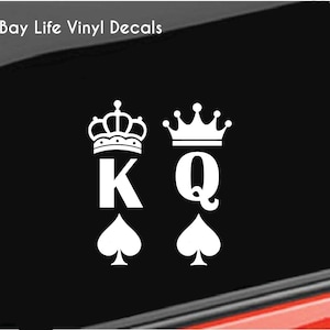 May include: White vinyl decal featuring a King and Queen of Spades design. The King and Queen are represented by the letters "K" and "Q", each topped with a crown and a spade symbol below. The text "Bay Life Vinyl Decals" is at the top.