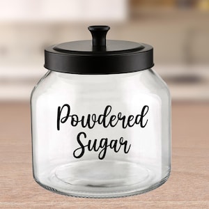 May include: A clear glass jar with a black lid and a black label that says "Powdered Sugar".
