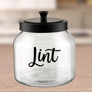May include: A clear glass jar with a black lid and a black vinyl label that says "Lint".