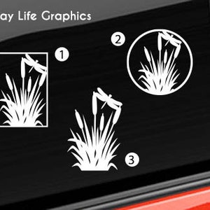 May include: Three different designs of a white silhouette of cattails and dragonflies. The designs are numbered 1, 2, and 3. The design in number 1 is a rectangle, the design in number 2 is a circle, and the design in number 3 is a free-form shape.