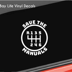 May include: White vinyl decal with the text "Save the Manuals" and a stylized image of a car's gear shift pattern.