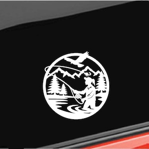 May include: White die-cut decal featuring a circular design of a person fly fishing in a river, with mountains, trees, and a soaring bird in the background. The design is set against a black background.