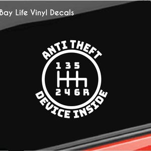 May include: White vinyl decal with the text "Anti Theft Device Inside" and a gear shift pattern with the numbers 1, 3, 5, 2, 4, 6, and R.