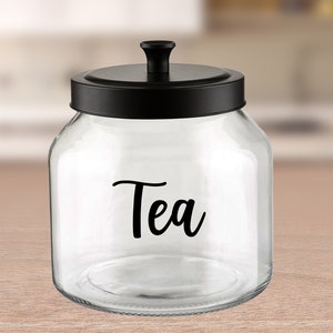 May include: A clear glass jar with a black lid and a black label that says "Tea".