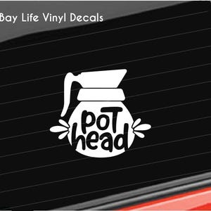 May include: White vinyl decal of a coffee pot with the text "pot head" on a black car window.