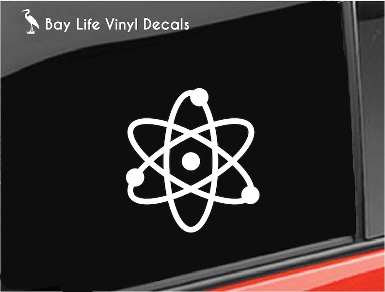 May include: White vinyl decal of an atom with a nucleus and orbiting electrons. The decal is on a black background.