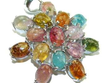 May include: A silver pendant with a cluster of 15 oval-shaped gemstones in various colors, including pink, green, blue, and yellow. The pendant is set in a silver starburst design.