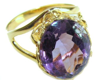 May include: A gold ring featuring a large, faceted, oval-cut amethyst gemstone. The amethyst displays shades of purple and violet. The ring's band has a unique, flowing design, and the gemstone is set in a decorative gold setting.