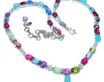 May include: A silver necklace with a heart-shaped design featuring a variety of colorful gemstones, including pink, blue, green, and purple.