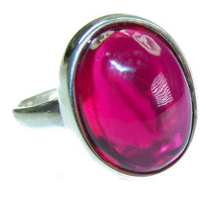Puede incluir: Un anillo de plata con una gran piedra preciosa ovalada de color fucsia. La piedra preciosa está engastada en una banda de plata pulida. El diseño del anillo es simple pero elegante. El anillo es adecuado para el uso diario o para ocasiones especiales. La piedra mide unos 2 cm de largo.