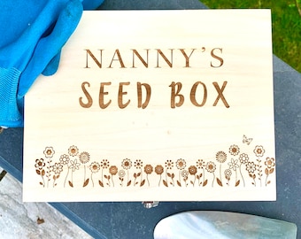 May include: A wooden box with the words "Nanny's Seed Box" engraved on the front. The box has a decorative border of flowers and a butterfly.