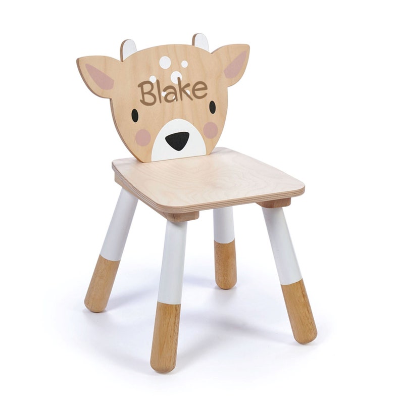 May include: A wooden children's chair with a deer head backrest. The chair is painted white and brown and has the name "Blake" printed on the front.