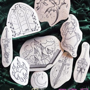May include: A collection of fantasy-themed fabric patches with black line art designs. The patches include images of a dragon, a castle, a sword, a key, a potion bottle, a crescent moon, and a heart with flames. The text "Fantasy Theme Stick & Stitch Pack" is also visible.