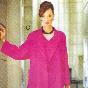 May include: A woman wearing a hot pink coat with a black necklace and black heels. She is carrying a black handbag with a gold clasp.