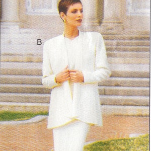 May include: A white blazer and skirt suit with a simple design. The blazer has a long, flowing style and the skirt is knee-length. The model is wearing the suit with a simple white top and brown heels.
