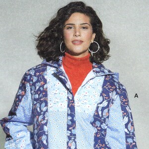 Op de afbeelding: Een blauw en wit gepatroneerd jack met een rode turtleneck eronder. Het jack heeft een ritssluiting en een trekkoord aan de onderkant.