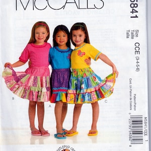 May include: A sewing pattern for a girl's dress with a ruffled skirt. The pattern is for sizes 3-4-5-6 and is from McCall's. The pattern is called CCE and the number is M5841.