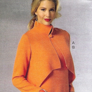 May include: A woman is wearing a bright orange jacket with a mandarin collar and a single button closure. The jacket has a draped front and long sleeves. She is also wearing a matching orange dress.