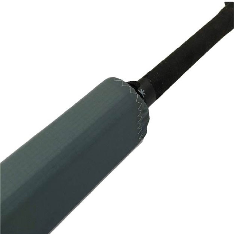 May include: Close-up of a gray umbrella shaft with a black handle. The shaft is covered in a gray fabric with a stitched seam.