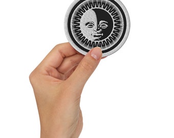 Può includere: Una toppa ricamata in bianco e nero con un design di sole e luna. Il sole e la luna hanno un viso sorridente.