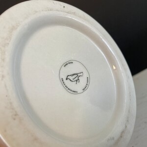May include: White ceramic mug with a black bird design and the text "Hand Wash, Made in China, Fabrique en Chine" on the bottom.