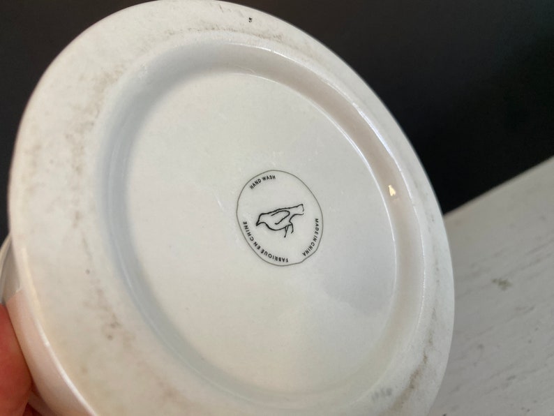 May include: White ceramic mug with a black bird design and the text "Hand Wash, Made in China, Fabrique en Chine" on the bottom.