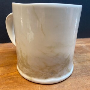 Puede incluir: Taza de cer&aacute;mica color crema con dise&ntilde;o veteado en tonos beige y marr&oacute;n. La taza tiene una base redondeada, un asa curvada y un acabado liso y brillante. Adecuada para bebidas fr&iacute;as o calientes.