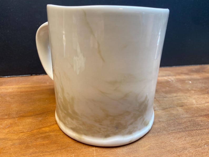 Puede incluir: Taza de cer&aacute;mica color crema con dise&ntilde;o veteado en tonos beige y marr&oacute;n. La taza tiene una base redondeada, un asa curvada y un acabado liso y brillante. Adecuada para bebidas fr&iacute;as o calientes.