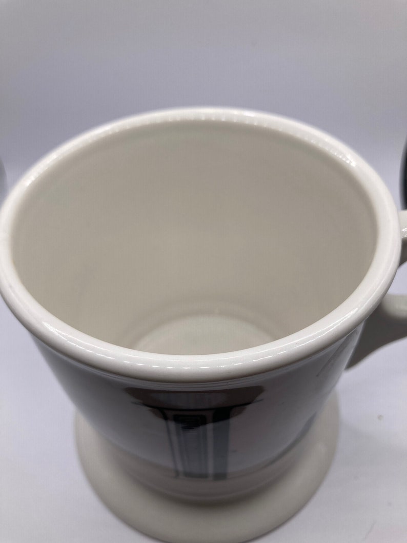 May include: White ceramic shaving mug with a black and grey design. The mug has a wide, round base and a handle.