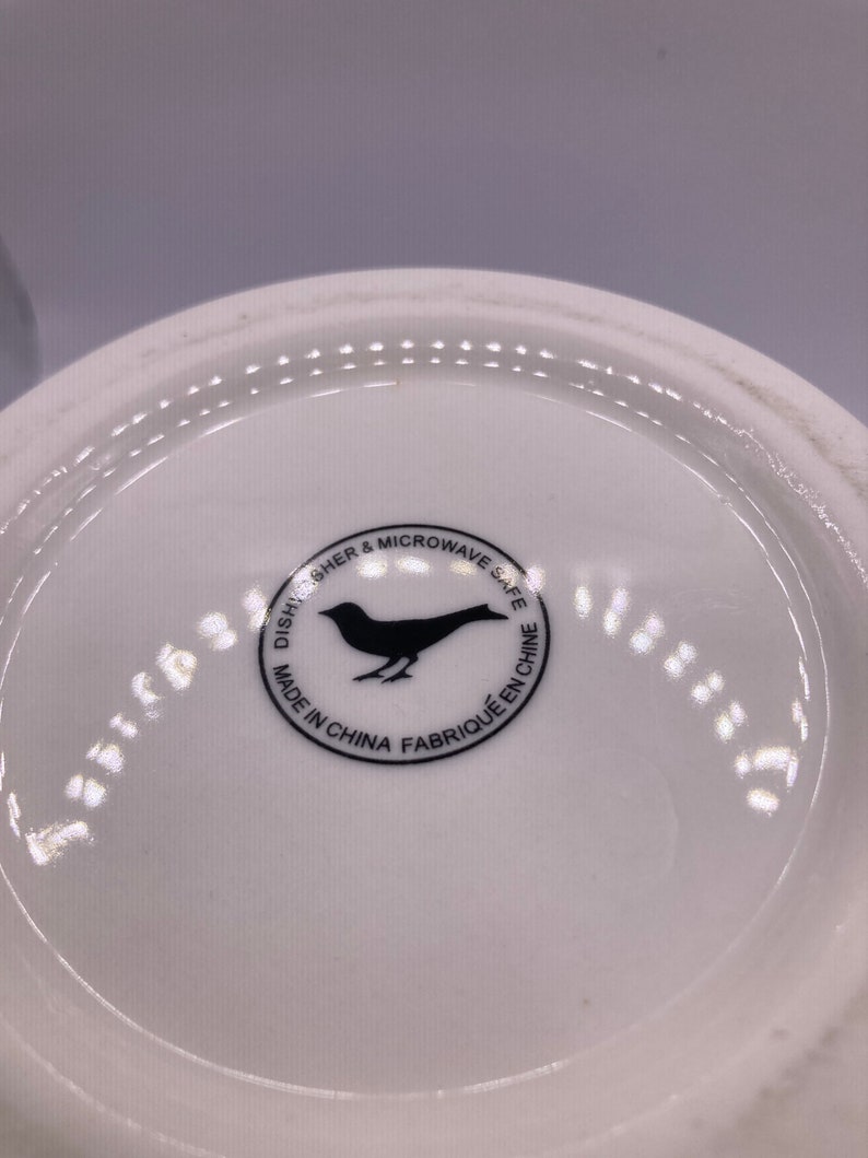 May include: White ceramic plate with a black bird logo that reads "Dishwasher & Microwave Safe Made in China Fabriqu&eacute; en Chine"