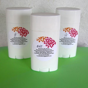 May include: Three white deodorant sticks with labels featuring a floral design and the text "Randalia Bee Hiven Persimmon Deodorant 2.5oz Infused Persimmon, Grapeseed Oil, Mango, Shea Butter, Beeswax, Calendula Oil, Pink Himalayan Salt, Arrowroot Powder randaliafarm@gmail.com".