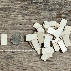 May include: A pile of small, unfinished, rectangular wooden shapes, approximately the size of a US quarter. The shapes are made of light-colored wood and are perfect for crafting projects.