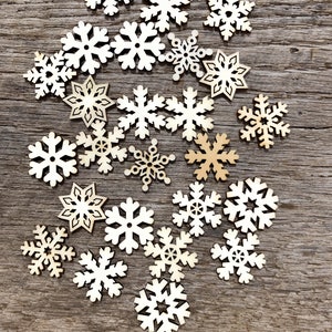 May include: A collection of wooden snowflake ornaments in various sizes and designs, scattered on a rustic wooden background.